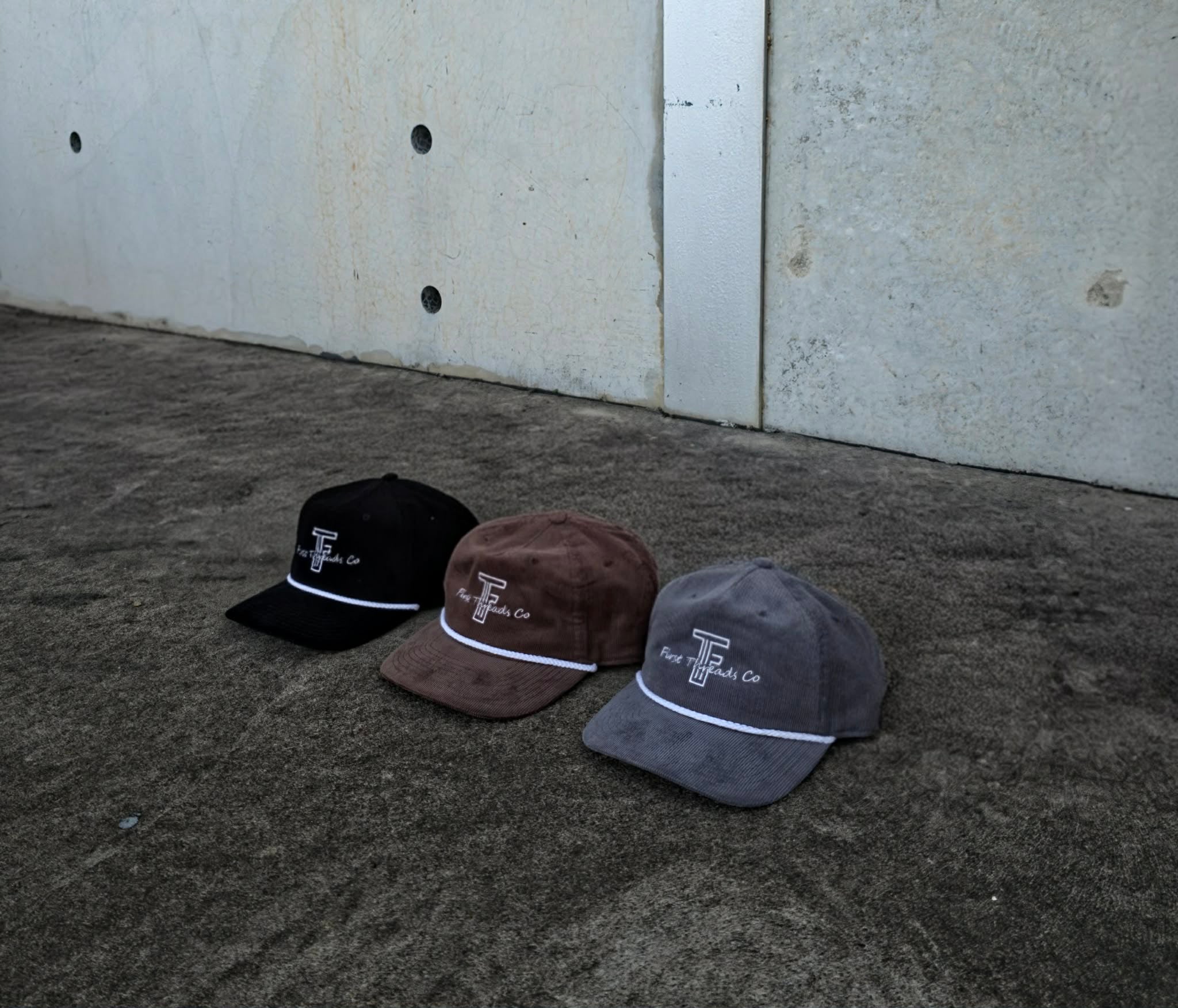 Three caps placed on a concrete surface against a plain wall.