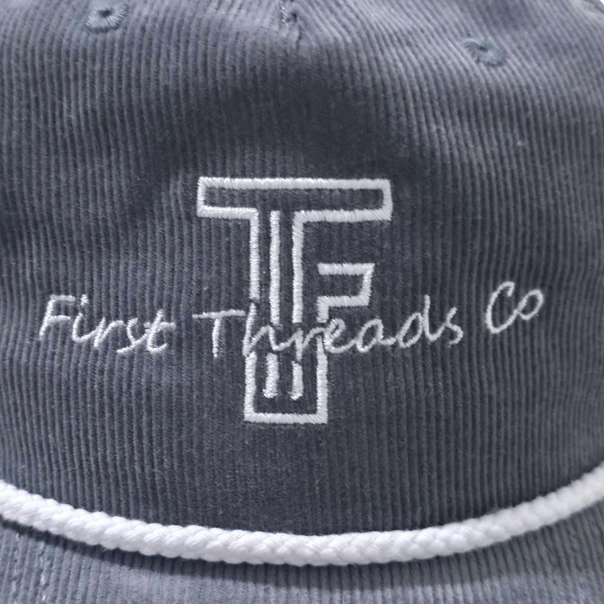 Gray cap with 'First Threads Co' logo and text on a close-up view